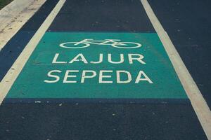 Bicycle lane sign in yellow with solid lines on asphalt road in Indonesia photo