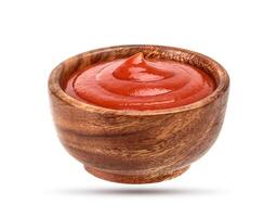 Ketchup in wooden bowl isolated on white photo