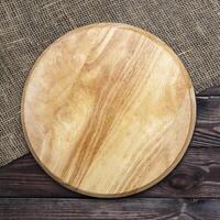 Round cutting board on a wooden table, top view photo