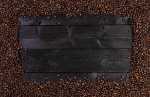 Frame made of roasted coffee beans on black wooden background, top view photo