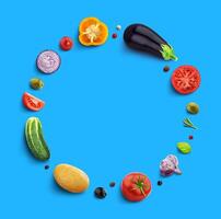 Vegetables on blue background, top view, round frame of vegetable with empty space for text photo