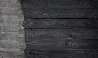 Old burlap fabric napkin on black wooden background, top view photo