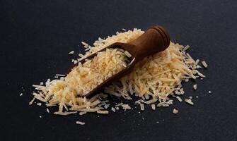 Grated parmesan cheese on black background photo