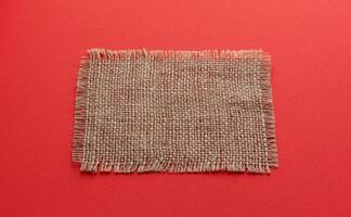 Burlap napkin on red color background photo