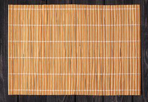 Bamboo mat on wooden table, top view photo