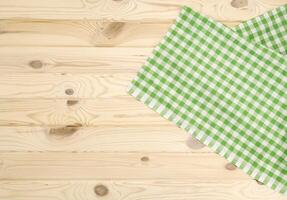 Green checkered tablecloth on wooden table photo