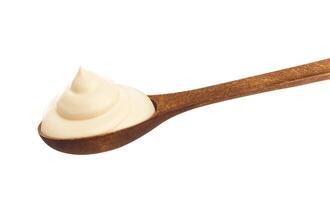 Sour cream in wooden spoon isolated on white background photo