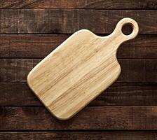 Cutting board on dark wooden table, top view photo