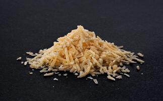 Grated parmesan cheese on black background photo