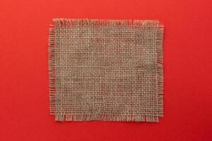 Burlap napkin on red color background, top view photo