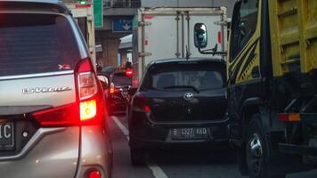 cerca arriba foto de un espalda lámpara de coche ese atascado en un tráfico mermelada en el carretera, con un bokeh antecedentes.