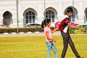 Kuala Lumpur, Malaysia on May 21, 2023. An older brother and a younger sister are playing on the Dataran merdeka field photo