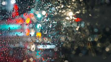 luces de el noche ciudad y paso carros mediante un mojado lluvioso ventana. video