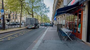 tranquilo parisino calle escena con al aire libre café asientos y bullicioso tráfico, capturado en París, Francia en abril 14, 2024, evocando todos los días urbano vida foto