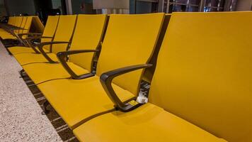 Empty yellow modern seating in an airport waiting area, signifying concepts of travel, transportation, and business trips, related to holiday travel season photo