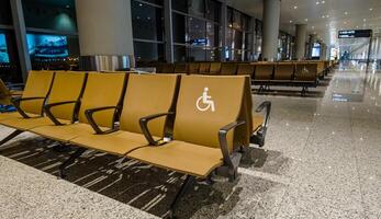 Empty airport waiting area with rows of brown seats and designated handicapped seating, indicative of travel, accessibility, and modern transportation hubs photo