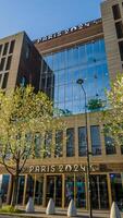 Modern building facade with Paris 2024 logo, symbolizing Olympic Games, on a sunny day in Paris, France, captured on April 14th, 2024, with spring bloom photo