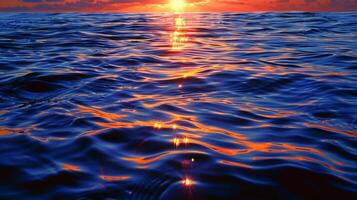 The setting sun reflects hues of orange gold and pink on the calm surface of the deep blue ocean. 2d flat cartoon photo