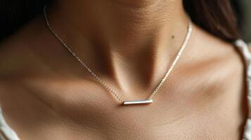 A minimalist necklace with a tiny silver bar pendant photo