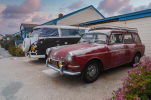 Clásico Volkswagen autobús y rojo estación vagón estacionado cerca azul edificio en California costa foto