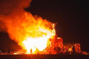 Dramatic Night Fire Scene with Structure Engulfed in Desert. photo