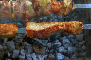 Cooking kebabs on a grill with smoke. Fresh brown BBQ meat cooked on an outdoor grill photo