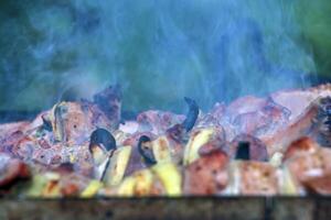 Cooking kebabs on a grill with smoke. Fresh brown BBQ meat cooked on an outdoor grill photo