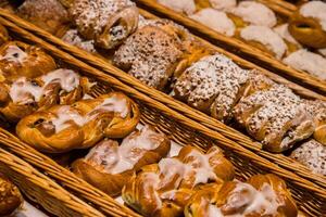 A lot of sweet pastries in baskets on the counter in the food store. Bakery on the buffet table. Business breakfasts and catering at events. Various bread type on shelf. Close-up. Selective focus. photo