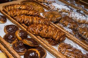 A lot of sweet pastries in baskets on the counter in the food store. Bakery on the buffet table. Business breakfasts and catering at events. Various bread type on shelf. Close-up. Selective focus. photo