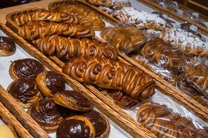 A lot of sweet pastries in baskets on the counter in the food store. Bakery on the buffet table. Business breakfasts and catering at events. Various bread type on shelf. Close-up. Selective focus. photo