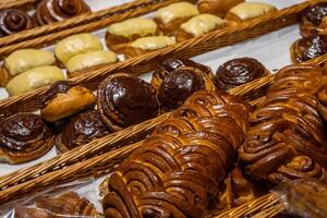 un lote de dulce pasteles en cestas en el mostrador en el comida almacenar. panadería en el buffet mesa. negocio desayunos y abastecimiento a eventos. varios un pan tipo en estante. de cerca. selectivo enfocar. foto