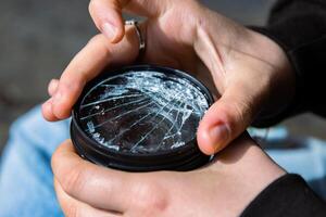 Photographer unscrewing broken lens filter from DSLR photo camera with after if fall down onto the floor. Close up. Destroyed cracked glass of photo-filter. Macro. Top view. Selective focus.