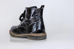 lado ver de uno muy desgastado bota. antiguo usado roto negro cuero cordón alto bota. de moda tobillo zapato. elegante De las mujeres de los hombres unisexo grunge bota con cordón. aislado en blanco antecedentes foto