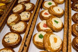 A lot of sweet pastries in baskets on the counter in the food store. Bakery on the buffet table. Business breakfasts and catering at events. Various bread type on shelf. Close-up. Selective focus. photo