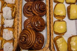 A lot of sweet pastries in baskets on the counter in the food store. Bakery on the buffet table. Business breakfasts and catering at events. Various bread type on shelf. Close-up. Selective focus. photo