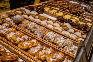 A lot of sweet pastries in baskets on the counter in the food store. Bakery on the buffet table. Business breakfasts and catering at events. Various bread type on shelf. Close-up. Selective focus. photo