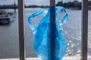 azul el plastico bolso colgando en el barandilla de elisabeth puente terminado donau río en budapest basura en el ciudad. ambiental contaminación concepto. ecológico desastre, catástrofe. selectivo atención foto