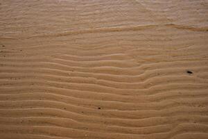 sin costura mojado arena con mar agua en un todo antecedentes. vacío ondulado arenoso mar abajo. exótico arenoso Oceano playa superficie. parte superior vista. simple, minimalista foto. ideal concepto para bandera, póster, anuncios foto