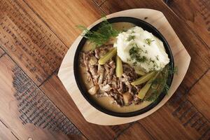 Beef stroganoff with mushed potatoes and pickled cucumbers photo