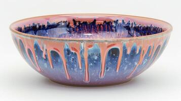 A closer look at a bowl with a glossy dripping glaze in shades of pink purple and blue resembling a watercolor painting created through soda firing. photo