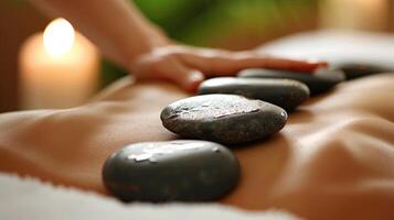 A massage the is using hot stones on a patients back after the patient has spent time in an infrared sauna releasing tension and promoting circulation. photo