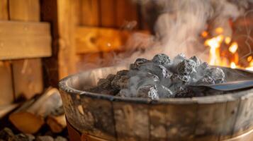 A steam bucket of hot stones being poured onto the coals producing a burst of steam and heat to intensify the sauna experience. photo