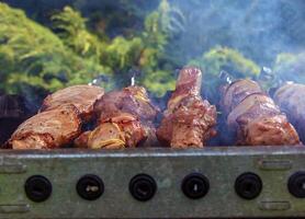 Cooking kebabs on a grill with smoke. Fresh brown BBQ meat cooked on an outdoor grill photo