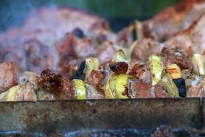 Cooking kebabs on a grill with smoke. Fresh brown BBQ meat cooked on an outdoor grill photo