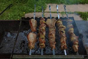 Cocinando kebabs en un parrilla con fumar. Fresco marrón barbacoa carne cocido en un al aire libre parrilla foto
