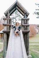 Little girl going down a wooden slide on a playground in a park photo