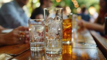 A group of friends sits at a long wooden table each holding a small glass of carbonated liquid in front of them photo