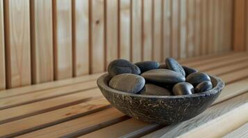 A bowl filled with smooth stones inside the sauna ready for use in a heat and cold therapy massage to release builtup tension. photo