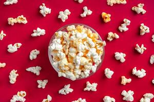 Scattered tasty cheese popcorn in bowl isolated on red background with copy space photo