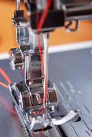 moderno de coser máquina prensador pie con rojo hilo cerca arriba foto
